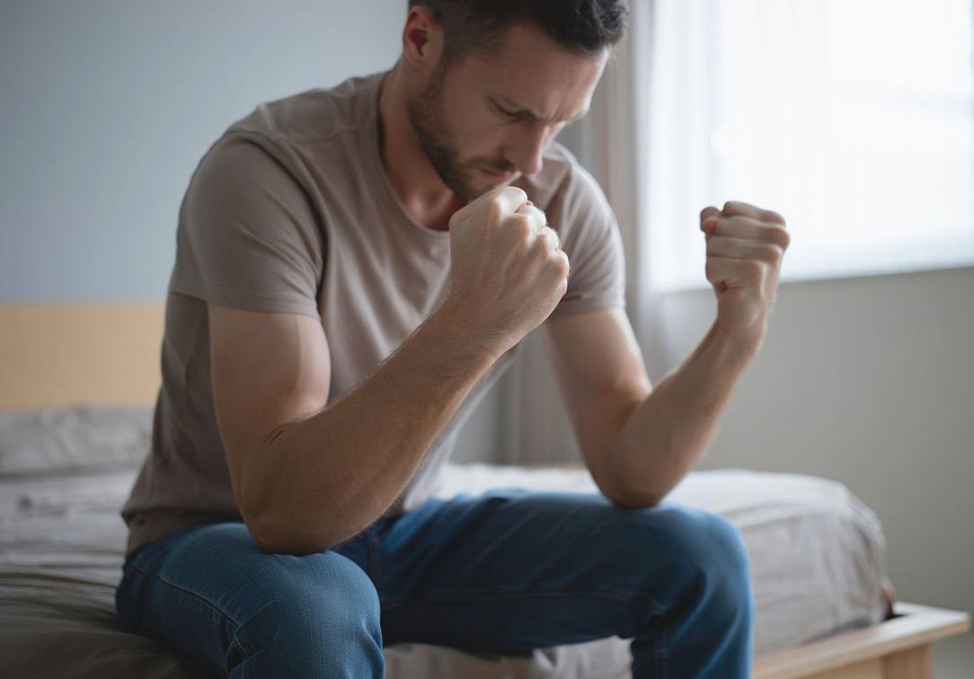 Мужчина злится сидя на кровати